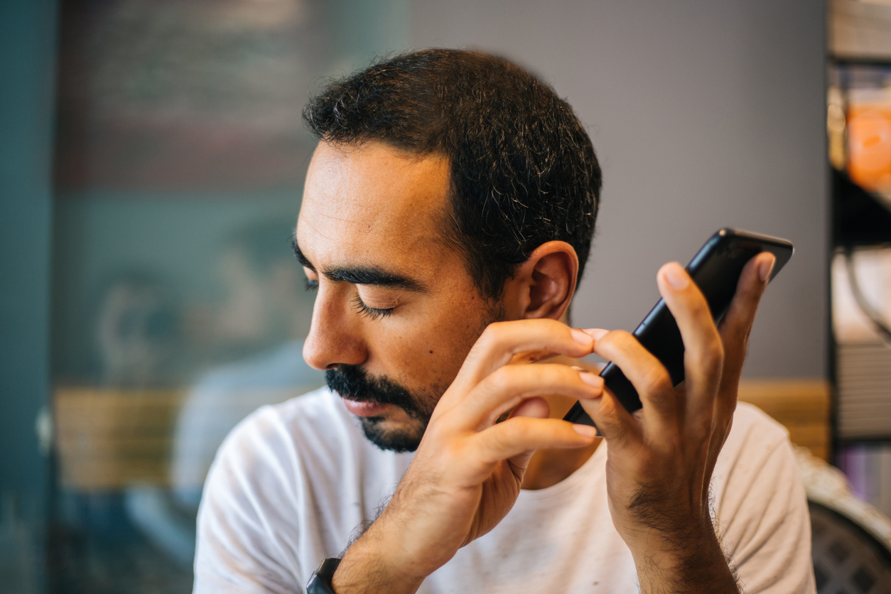 Homem cego ouvindo instruções no celular